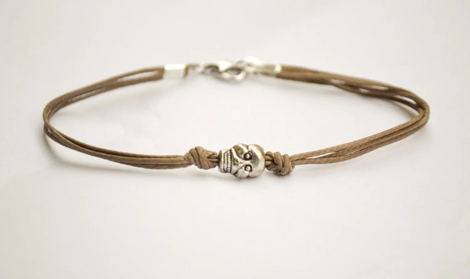 Men's bracelet with a silver skull charm and a brown cord